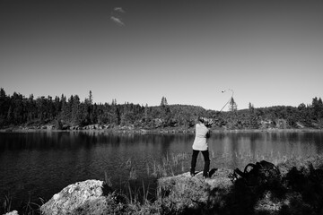 A young girl fishes in a small lake in the wild nature of Norway, Hallingdal, Gol. Shot in black...