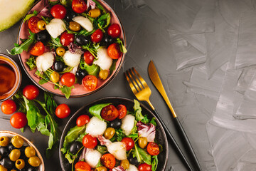  Two servings of Italian salad with melon and vegetables on a concrete background. Vegan food