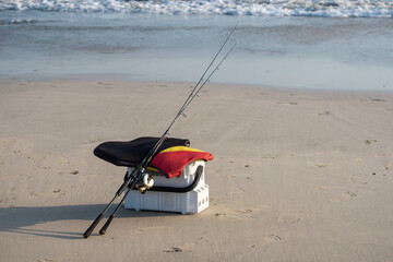 Fishing equipment on the beach: white box, fishing rods, vest