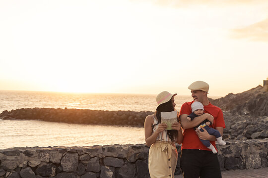 Happy young family walking near the beach, day with a perfect sunset.  Sunset, travel and holiday concept - Image