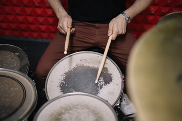 Shot of an unrecognizable man playing the drums. Cropped view of man playing drums using wooden...