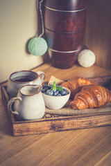 romantic breakfast with fresh croissants coffee,milk and berries on wooden table
