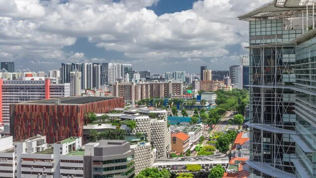 Singapore skyline with Victoria street and National Library aerial timelapse hyperlapse. Green trees on the road with traffic. Clouds on a blue sky
