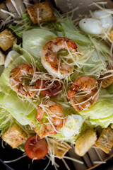 Caesar salad with prawns on a plate in a cafe