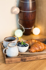romantic breakfast with fresh croissants coffee,milk and berries on wooden table