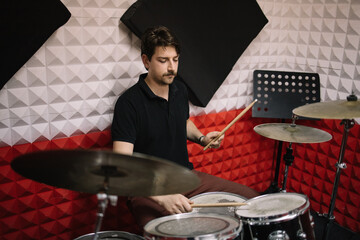 Drummer man playing drums set during rehearsal in studio. Young male musician playing drums and...