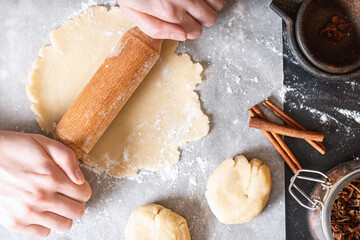 Female hands roll out the dough for a pie or cookies top view. Homemade baking.