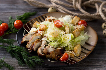 Caesar salad with chicken on a striped plate in a cafe