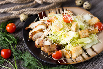 Caesar salad with chicken on a striped plate in a cafe