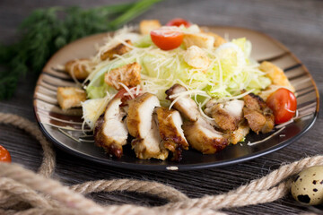 Caesar salad with chicken on a striped plate in a cafe