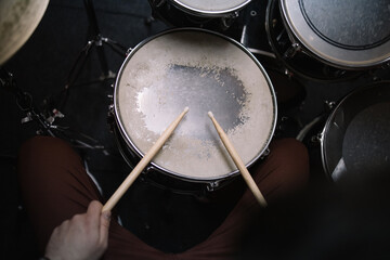 Hands of male drummer holding drumsticks over drum. Close-up view of professional drum set and male hands.