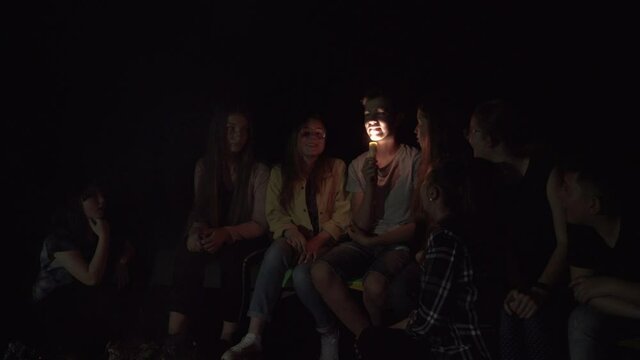 Teenager telling scary story using flashlight on face.