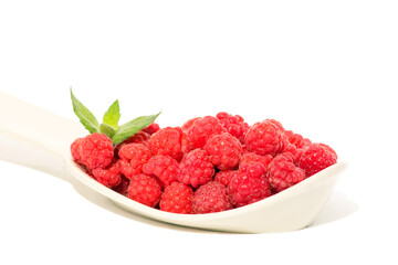 Ripe forest red raspberries on a large plastic spoon, isolated on white background. 