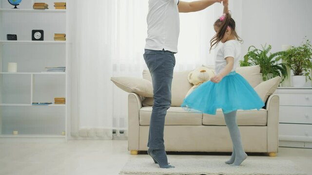 Father is dancing with his daughter. Little ballerine is dancing around.