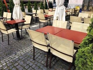 Street view from street tables of a Lviv outdoor cafe with empty tables and chairs. rows of wicker chairs and square tables in outdoor canteen or restaurant. No people coronavirus quarantine, takeaway