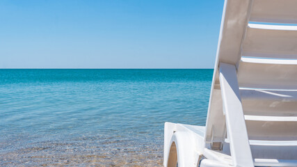 chair on the sea edge view, summer light sky, no clouds, afternoon sand beach