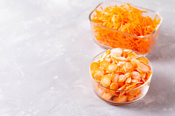 Frozen slices of carrots in a glass container on a light background
