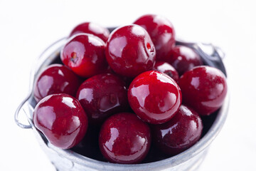 ripe cherries in a metal bucket on a white background