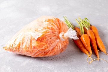 Frozen grated carrots in plastic bags on a light background