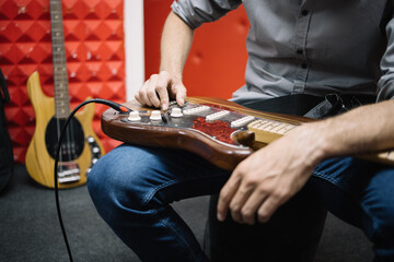 Close-up view of male musician with electric guitar. Cropped image of hands of male guitar player...