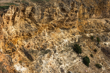 Texture of a sandy rock in close-up against the sea. Yellow loose rock. Stone natural red background. Steep sea shores.