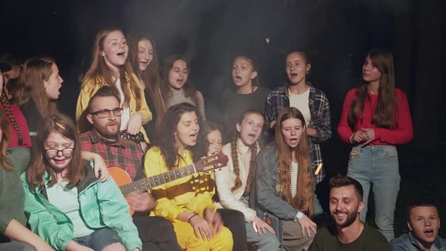 Kids singing near camp fire.