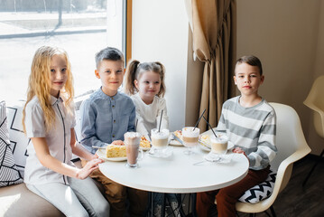 A large friendly company of children celebrate the holiday in a cafe with a delicious dessert. The day of the birth