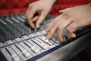 Cropped man adjusting channel on DJ mixing controller. Close-up view of human hands tuning music mixer