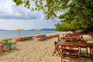 Beautiful tropical paradise beach with sun beds under coconut palm trees on island. Beautiful beach and beautiful palm tree travel summer holiday concept.