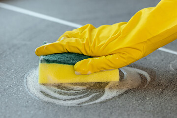 Woman's hands in yellow gloves cleaning counter top in kitchen