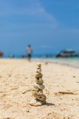 Fototapeta na wymiar Pyramid of stones on a sandy beach. White sand, coral beach. The concept of life balance, harmony and meditation. stability, zen, harmony, balance.