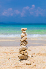 Fototapeta na wymiar Pyramid of stones on a sandy beach. White sand, coral beach. The concept of life balance, harmony and meditation. stability, zen, harmony, balance.