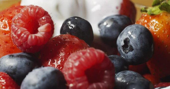 Pouring yogurt on fresh berries in slow motion. Pouring Strawberries, Raspberries and Blueberries With Yogurt in Slow Motion. Fresh berries are poured with yogut.