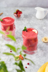 banana and strawberry cocktail in a glass with mint leaves in the sun