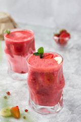 banana and strawberry cocktail in a glass with mint leaves in the sun