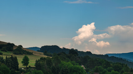 Cumulus congestus or towering cumulus - on the blue sky over hilly landscape