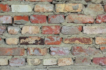 Part of a brick wall with bricks of different colors.