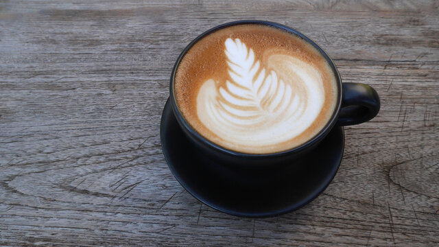 Top view hot coffee cappuccino latte art flower shape in ceramic cup on wooden table background