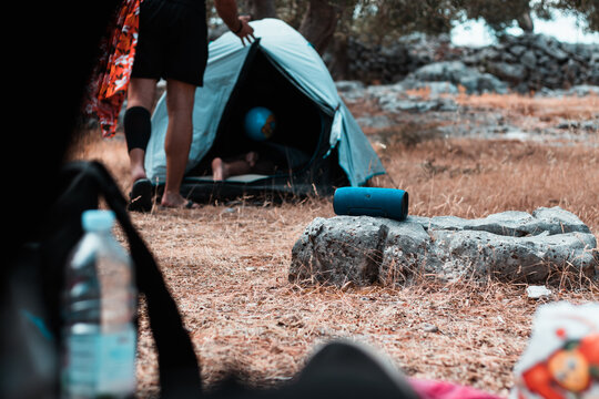 Wireless speaker standing on a rock outside, tents around it, camping in the nature and listening to music