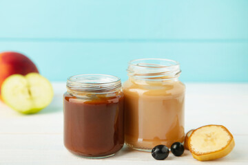 Glass jars with nutrient baby food on blue background