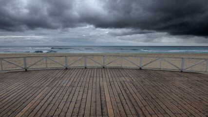 Paesaggio di mare con pavimento in legno e nuvole all'orizzonte.