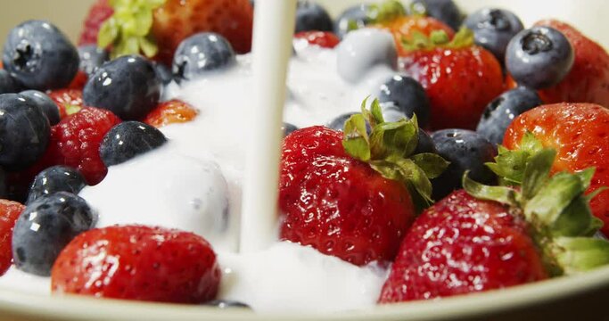 Pouring Strawberries, Raspberries and Blueberries With Yogurt in Slow Motion. Fresh berries are poured with yogut.