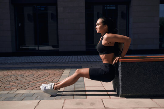 Young sporty teenage model pumps and crunches the abdominals and posing on playground near horizontal and parallel bars.