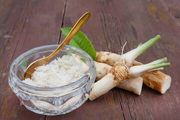 Horseradish grated in glassware and roots