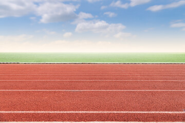 Running track with copy space. Empty athlete track with grasses, blur cloud and blue sky.
