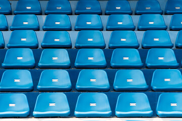 Blue stadium seats with number. Empty plastic chairs in stadium.