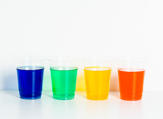 Four glasses with liquids of different colors on white background.