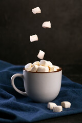 Hot chocolate with falling marshmallow on dark background