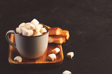 Hot chocolate with marshmallow and crusty buns on dark background