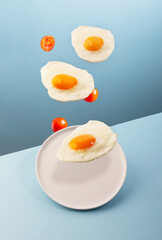 Three flying eggs and a plate on the modern blue background